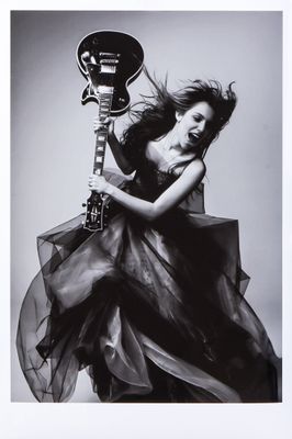 black and white photograph of a woman in a dress holding a guitar