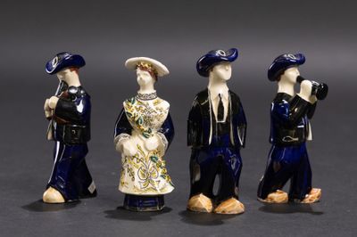trois figurines représentant des personnes vêtues de bleu et de blanc, debout les unes à côté des autres