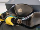 pair of black and yellow high heeled shoes sitting on top of a black box