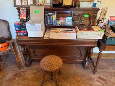 un piano et un tabouret dans une pièce où se trouvent de nombreux cartons