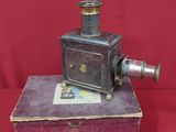 an old fashioned camera sitting on top of a box on a red surface