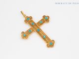 a close up of a gold cross with turquoise stones on it