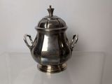 an antique silverplated teapot with a lid on a clear shelf