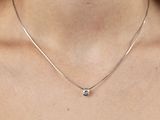 Cette femme porte un collier en argent orné d'un diamant noir.