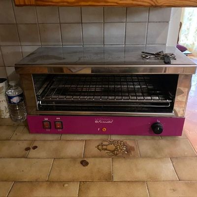 un four grille-pain posé sur le carrelage d'une cuisine