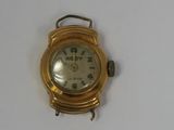 a gold wrist watch with a white face on a white surface