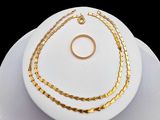 une assiette blanche sur laquelle sont posés un collier en or et une bague en or