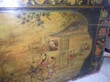 an old painted box sitting on the floor next to a chair