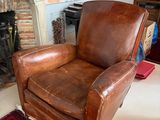 a brown leather chair sitting in front of a fire place