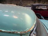 an old blue car parked in a parking lot with other cars