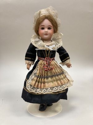 une poupée ancienne en porcelaine représentant une femme vêtue d'une robe et d'un bonnet