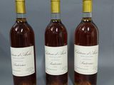 trois bouteilles de vin sont alignées sur une surface grise