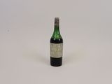 une vieille bouteille de vin posée sur une surface blanche