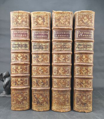 four old books are stacked on top of each other on a table