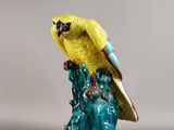 figurine représentant un perroquet perché sur un rocher, sur fond gris