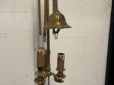 a tall brass clock with a bell and candles on it