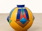 yellow vase with blue and red design on it sitting on a table