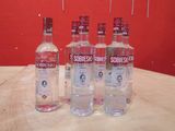 quatre bouteilles de vodka posées sur une table devant un fond rouge