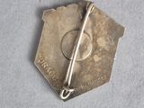 a silver pin with a pin on it on a gray surface