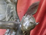 une statue représentant un ange tenant une horloge dans ses mains