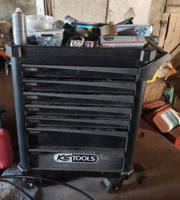 un chariot à outils noir sur lequel se trouvent de nombreux outils