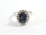 un gros plan d'une bague en saphir et diamants posée sur une surface blanche
