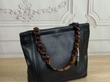 a black leather handbag with tortoises on the handle