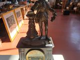 une statue représentant un homme tenant une horloge dans une pièce