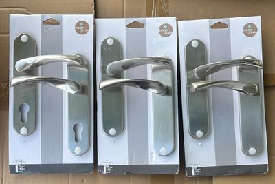 trois poignées métalliques argentées sur une boîte en carton, elle-même placée dans une autre boîte en carton