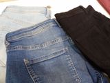 three pairs of jeans sitting on top of each other on a table