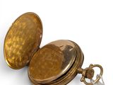 a gold pocket watch with a chain on a white background