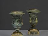 une paire d'urnes antiques en bronze sur des socles, sur fond gris