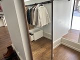 a mirror in the corner of a room with clothes on hangers