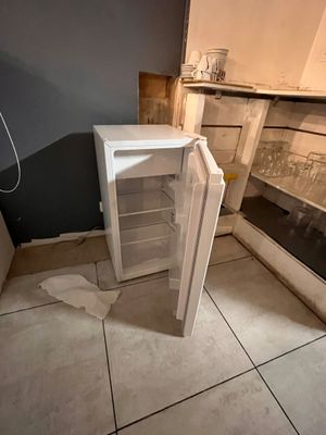 a small white refrigerator in the corner of a kitchen