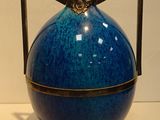 a blue vase sitting on a table with a black handle