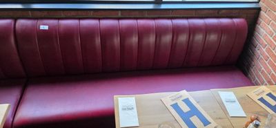 a red booth with a red leather bench and a window