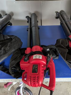 un ventilateur rouge posé sur une table bleue, à côté de deux ventilateurs noirs