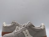 a pair of grey sneakers with brown soles on a white background