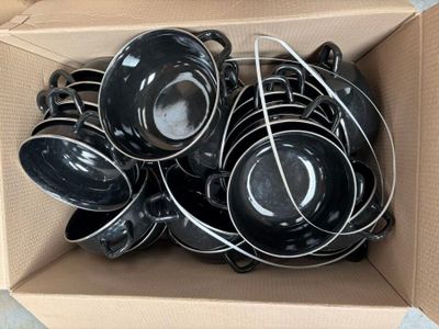une boîte en carton remplie d'un tas de casseroles et poêles noires