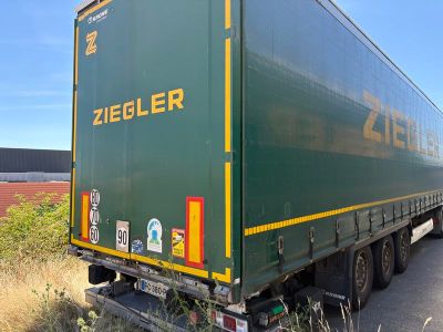 un semi-remorque vert garé sur le bord de la route