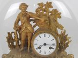 a gold clock with a man and a woman in a glass dome