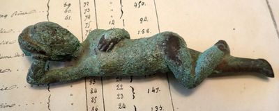 a bronze figurine of a baby laying on a sheet of paper