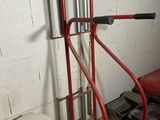 a red hand truck with a metal handle in a garage