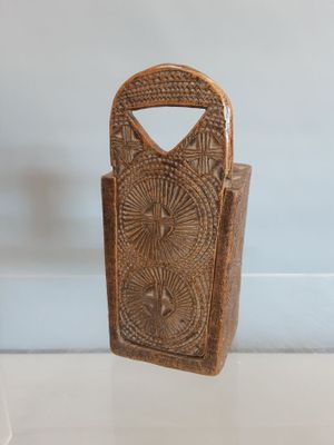 un petit porte-monnaie en bois exposé sur une étagère vitrée