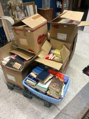 de nombreuses caisses de livres empilées les unes sur les autres par terre