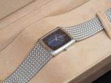 une montre en argent au cadran bleu, posée dans une boîte