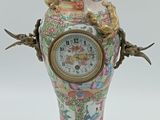 un vase surmonté d'une horloge, posé sur un socle