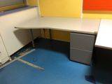 un bureau blanc avec un classeur noir dans un coin