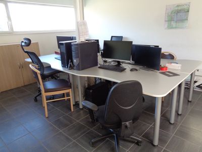 a desk with two computers and a chair in the room