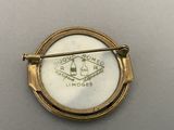 an image of a gold broochle with a white and black emblem